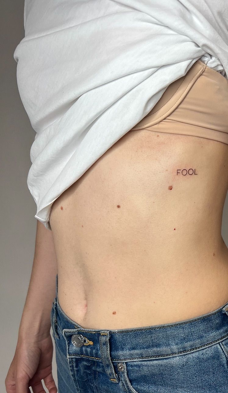 A tiny single-word tattoo on the ribs, two inches or less